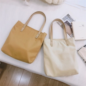 Detail of canvas tote bags with PU leather handles and golden rivet reinforcements