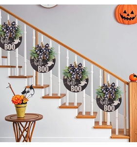 Detail of wooden Halloween BOO sign hanging on stairs with ribbons and greenery