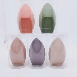 Gros plan de cinq éponges à maquillage colorées dans des étuis cylindriques