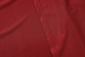 Detailed macro view of dark red knit fabric with durable double-stitched seam craftsmanship