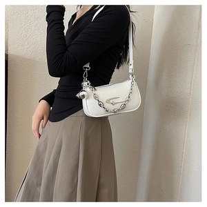 Close-up of white pleated crossbody bag with silver chain and metal star logo detail