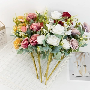 Close-up of artificial multi-head silk roses in various pastel colors and green leaves