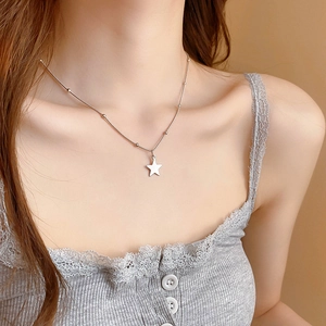 Close-up of a silver star pendant necklace worn on a model for casual styling