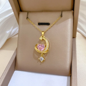 Detail of gold heart necklace with pink gemstone and zircon tassel in a jewelry box