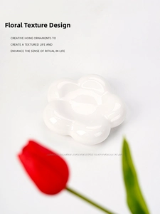 Macro detail of a white flower ceramic jewelry tray with a glossy finish and minimalist design
