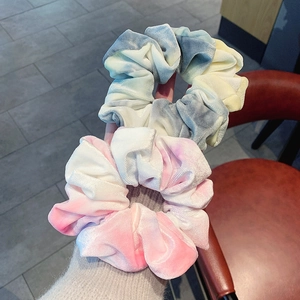 Close-up of velvet scrunchies in pink and blue tie-dye gradients with soft textures