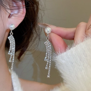 Detail view of silver tassel earrings with white pearls and sparkling rhinestone chains