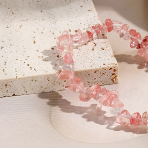 Macro detail of irregular pink natural stone beaded elastic bracelet on a stone display
