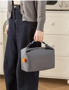 Close-up of insulated dark gray lunch bag with adjustable buckle strap and orange tag