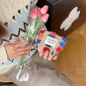Dettaglio della borsa in peluche marrone con pompon colorati e zip in metallo