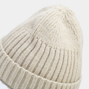 Nahaufnahme der cremeweißen Rippstrickstruktur einer warmen Winter-Beanie