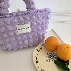 Close-up of lilac bubble textured fabric handbag with white rectangular logo patch