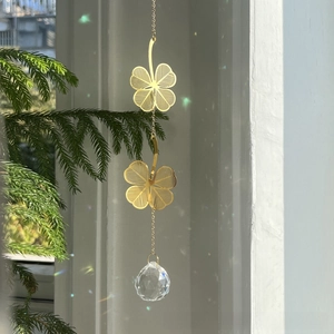 Close-up of golden four-leaf clover suncatcher with faceted crystal prism light effect