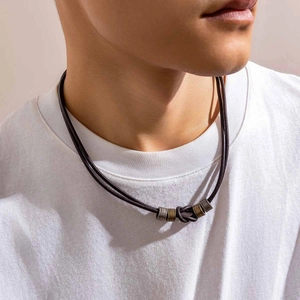 Close-up of men's leather knotted ring necklace with vintage bronze metal details