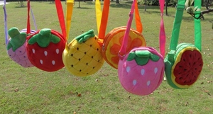 Selection of plush fruit cross-body bags including strawberry and grape on outdoor lawn