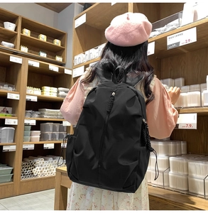 Close-up of black casual backpack with vertical zipper and side drawstring pockets