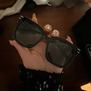 Detail of black square sunglasses with golden metal accents on a stylish frame