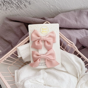 Détail de barrettes à nœuds en tissu rose faites à la main sur carte décorative
