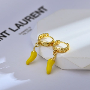 Macro shot of gold plated Cuban link hoop earrings with a bright yellow chili pendant
