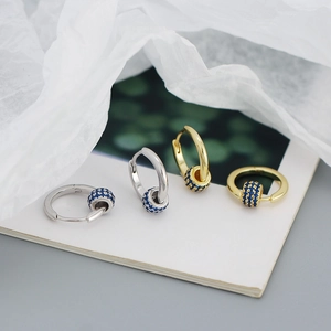 Detail view of gold and silver hoop earrings with rotating blue zircon beads