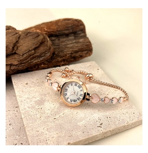 Détail d'une montre bracelet or rose avec gemmes cœurs roses et cadran à chiffres romains