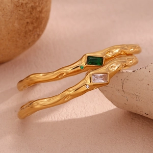 Detail of 18K gold plated wave textured bracelets with emerald and clear zircon stones