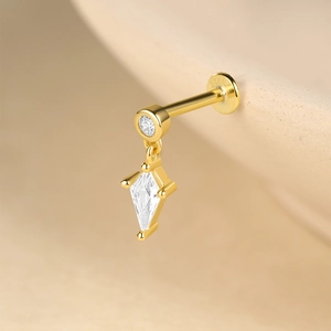 Macro d'un clou d'oreille en argent S925 doré avec zircon en losange et pendentif pompon