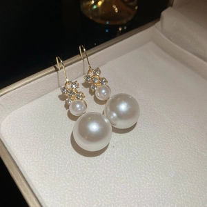 Primo piano di orecchini con perle dorate e fiocchi di strass in una scatola regalo
