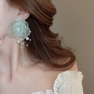 Detail of green lace flower earring with pearl tassel worn by a model