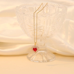 Collier cœur rouge avec chaîne dorée et détails en zircon blanc sur bord de verre
