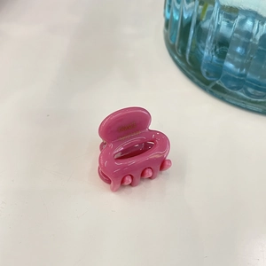 Detail of pink acetate hair claw clip featuring handmade gold France logo lettering