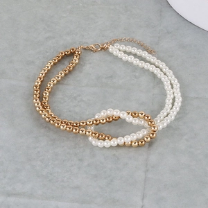 Detail of double-layered necklace featuring gold beads and white imitation pearls