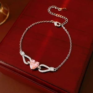 Close-up of pink heart gemstone bracelet with silver metal chain on red wooden gift box