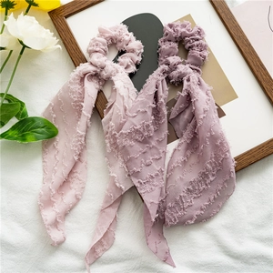 Detail of pink fabric scrunchies with long streamers and fringe edges on white background