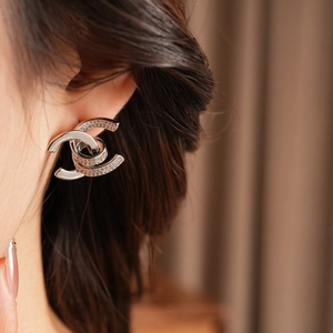 Macro shot of silver dual-C earrings with sparkling white zircons on a model ear