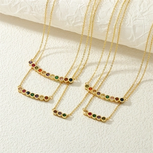 Close-up of stacked gold necklaces featuring vibrant rainbow-colored gemstone pendants