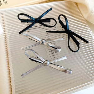 Close-up of black and silver faux leather bow hair clips on a glass tray in Y2K style