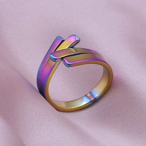 Macro shot of rainbow-plated stainless steel geometric ring on purple silk fabric