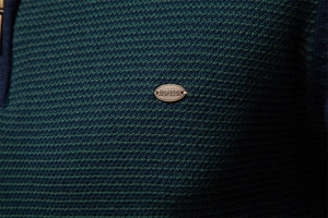 Détail de la texture en maille et de la plaque métallique sur un pull en tricot