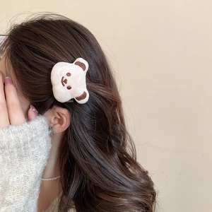 Close-up of a cute beige plush bear hair clip worn on side hair for a cozy daily look