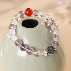 Detail of beaded bracelet with purple crystals, red bead and vintage silver Fu charm