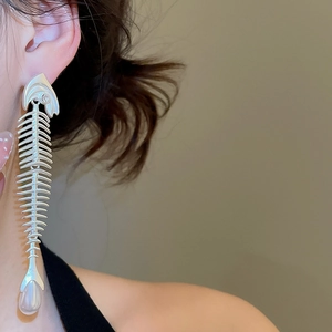Close-up of silver fishbone earrings with sparkling zircon and drop pearl on model