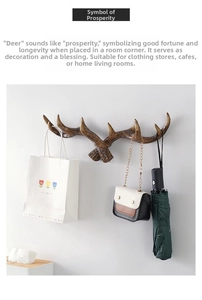 Detail of vintage stag antler wall hook holding bags and umbrellas on white wall