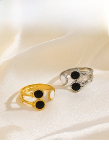 Detail of gold and silver open rings with black and white inlay on champagne silk fabric