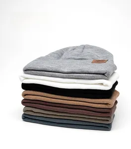 Vertical stack of multi-color thick knit beanies with premium leather logo detail