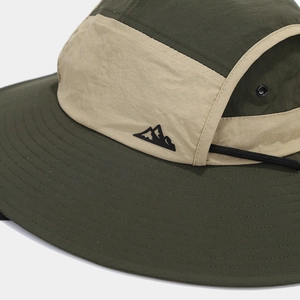 Detail of olive green sun hat showing breathable metal vents and mountain logo embroidery