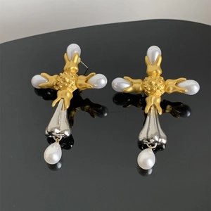 Close-up of vintage baroque cross earrings with pearls and silver tassels on black surface