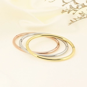 Polished minimalist hollow bangles in gold, silver and rose gold on a fabric background
