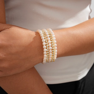 Close-up of elegant five-layer beaded bracelet featuring white pearls and rhinestones