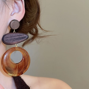 Detail view of ethnic wood and amber resin drop earring with tiered geometric pendants